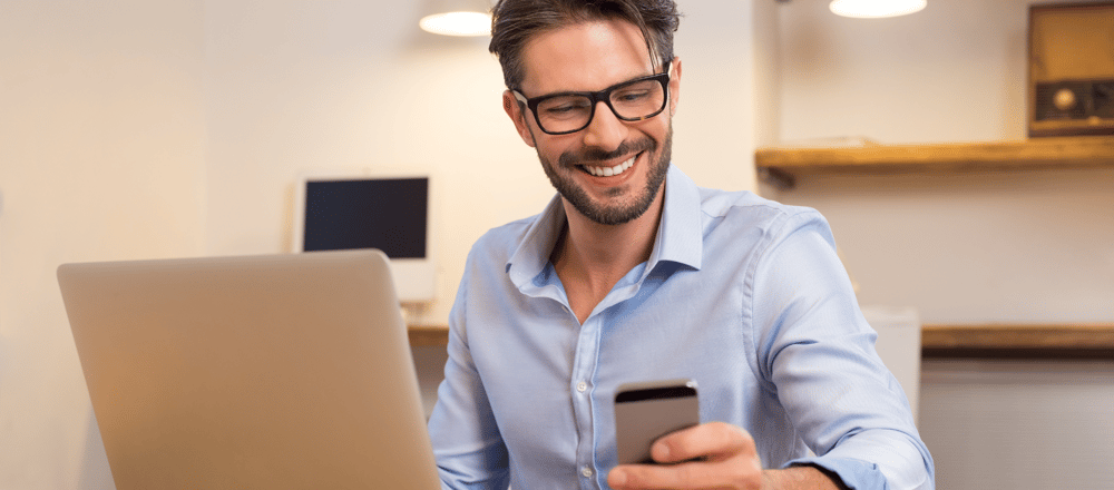 man achter bureau met telefoon in zijn hand