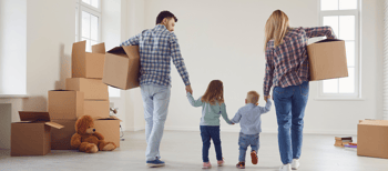 Man, vrouw en twee kleine kinderen lopen met verhuisdozen