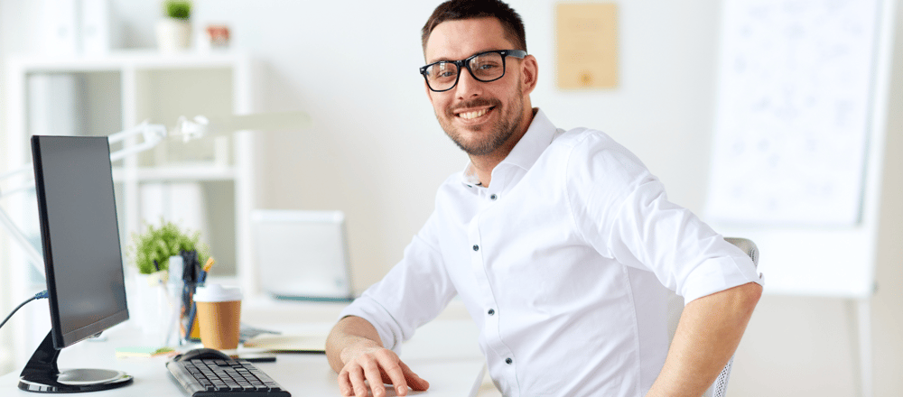 Glimlachende man met wit overhemd achter bureau